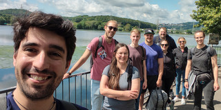 Eine Gruppe Menschen vor einem See.